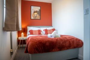 een slaapkamer met een bed met een oranje muur bij Comfortable 4 Bedroom Home in Milton Keynes by HP Accommodation with Free Parking, WiFi & Sky TV in Milton Keynes