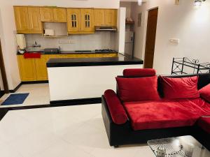 a living room with a red couch and a kitchen at Riviera palms phase 1, luxury apartment ,with swimming pool view Arpora - near baga beach flat no 123 in Old Goa