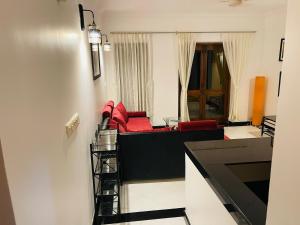 a living room with a black couch and red chairs at Riviera palms 1 Luxury 1 BHK apartment with Swimmimg Pool view- Arpora - near baga beach in Old Goa