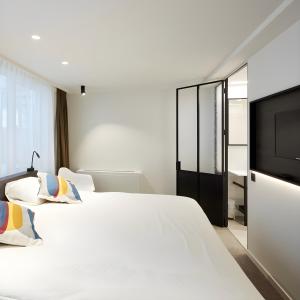 a bedroom with two beds and a flat screen tv at Hotel Nelson in Knokke-Heist