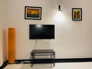a flat screen tv on a white wall with a stool at Riviera palms 1 Luxury 1 BHK apartment with Swimmimg Pool view- Arpora - near baga beach in Old Goa