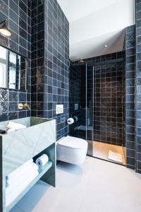 a bathroom with a tub and a toilet and a sink at Hôtel Le Mosaïque in Narbonne