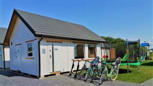 un petit hangar avec des vélos garés devant une aire de jeux dans l'établissement Domki letniskowe Sarbinowska Jaskółka, à Sarbinowo