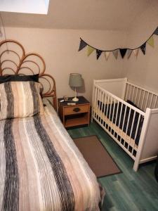ein Schlafzimmer mit einem Kinderbett und einem Bett mit einem Kinderbett in der Unterkunft L'école buissonnière 