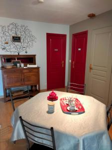 ein Esszimmer mit roten Türen und einem Tisch mit einem Teller Essen in der Unterkunft L'école buissonnière 