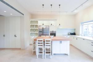 a kitchen with white cabinets and a kitchen island with stools at Tiny Bubbles by HolyGuest in Tel Aviv