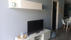a living room with a flat screen tv on a white cabinet at VILLA HERAIA in Marina di Ragusa