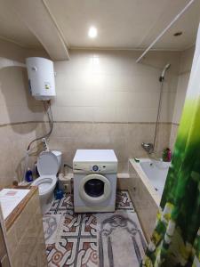 uma casa de banho com um WC e uma máquina de lavar roupa em Уютная трёхкомнатная квартира em Pavlodar