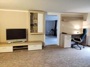ein Wohnzimmer mit Fernseher, Schreibtisch und Stuhl in der Unterkunft Geräumige Wohnung im Schwarzwald in Seelbach
