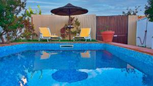 einen Pool mit 2 Stühlen und einem Sonnenschirm in der Unterkunft Vila Saraz in Campinho
