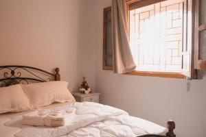 a bedroom with a white bed with a window at Santacruz Hostel in Tamraght Ouzdar