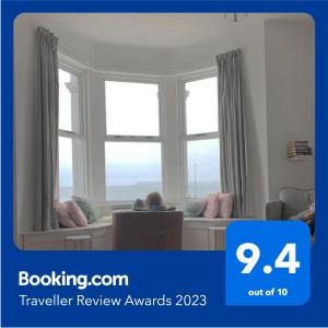 a woman sitting in a chair in front of a window at Stunning 3 bed seafront mansion building sleeps 6 adults or 8 with kids in Portrush