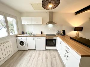 a kitchen with white cabinets and a washer and dryer at Appartement T3 cosy – Entre bourg et plages in Ploemeur