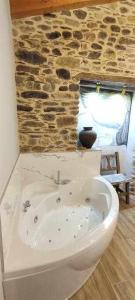 - białą wannę w pokoju z kamienną ścianą w obiekcie Precioso Apartamento 2 Hab con Bañera Hidromasaje w mieście O Barco de Valdeorras