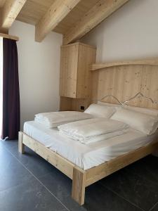 twee bedden in een slaapkamer met een houten hoofdeinde bij Dolomia Apartments & Spa in Dimaro