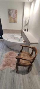 y baño con bañera y silla de madera. en Precioso Apartamento 1 Hab con Bañera Hidromasaje, en O Barco de Valdeorras