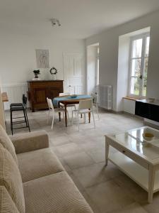 uma sala de estar com um sofá, uma mesa e cadeiras em Clos des Chardons - Le Jardin em Saint-Aignan