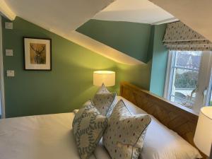 a bedroom with green walls and a bed with pillows at Myrtle Cottage B&B in Porlock