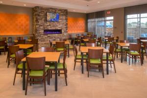 Fairfield Inn & Suites by Marriott Washington في واشنطن: غرفة طعام مع طاولات وكراسي ومدفأة