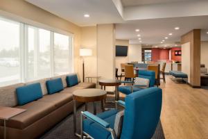una sala de espera con sofá, mesas y sillas en TownePlace Suites by Marriott Joliet Minooka, en Minooka