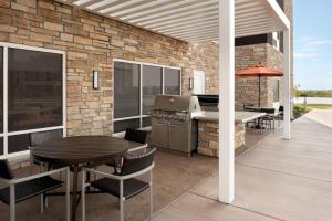 un patio con parrilla, mesa y sillas en TownePlace Suites by Marriott Joliet Minooka, en Minooka