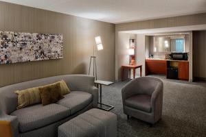 Courtyard by Marriott Columbus West/Hilliard في كولومبوس: غرفة معيشة مع أريكة وكرسي