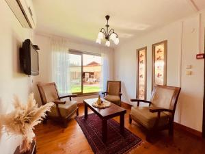 sala de estar con sillas, mesa y TV en איתן בקתות עץ Eitan Wood Cabins Resort, en Sede Eli‘ezer