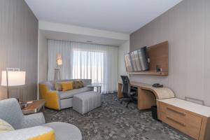 a hotel room with a desk and a couch at Courtyard by Marriott West Springfield in West Springfield