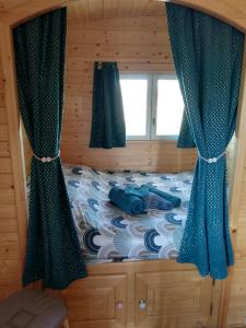 a bedroom with a bed with blue curtains and a window at Roulot'So Zen in Beslon