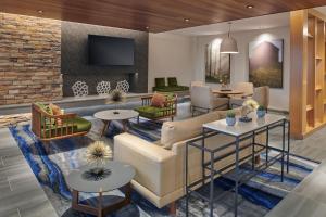 eine Lobby mit einem Sofa, Tischen und einem TV in der Unterkunft Fairfield Inn & Suites by Marriott Chicago O'Hare in Des Plaines
