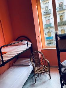 ナポリにあるDama HostelBBの二段ベッド2台、椅子、窓が備わる客室です。