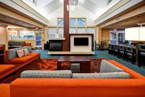 vestíbulo con muebles de color naranja y TV de pantalla plana en Residence Inn by Marriott Springfield Chicopee, en Chicopee