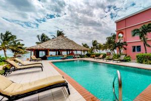 a resort swimming pool with chairs and a gazebo at Caribe Island Studio #2 in Belize City