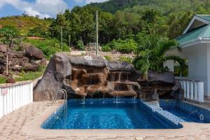 a swimming pool with a waterfall in a backyard at Ocean Blue Bay in Anse Volbert Village