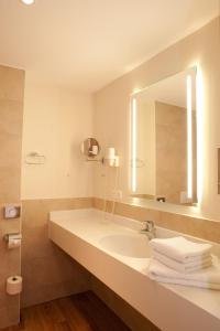 uma casa de banho com lavatório, espelho e toalhas em Janssens Hotel em Neuharlingersiel