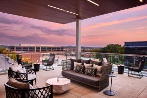 eine Terrasse mit einem Sofa und Stühlen auf dem Balkon in der Unterkunft AC Hotel by Marriott Nashville Brentwood in Brentwood