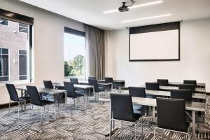 a conference room with tables and chairs and a projection screen at AC Hotel by Marriott Nashville Brentwood in Brentwood
