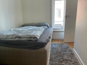 an unmade bed in a room with a window at Oslo center 4 in Oslo