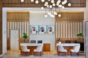 Residence Inn by Marriott Al Jaddaf في دبي: لوبي على طاولتين وكراسي ولوحات على الحائط