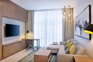 Residence Inn by Marriott Al Jaddaf في دبي: غرفة معيشة مع أريكة وتلفزيون