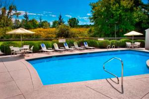 a swimming pool with chairs and umbrellas at Fairfield Inn by Marriott Burlington Williston in Burlington