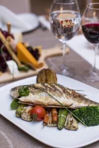 a plate of fish and vegetables with a glass of wine at Prive Hotel Bodrum - Adult Only in Bodrum City