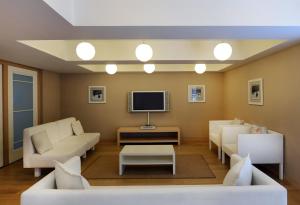 a living room with white furniture and a tv at Prive Hotel Bodrum - Adult Only in Bodrum City