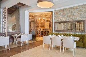 a restaurant with white tables and chairs and a stone wall at Prive Hotel Bodrum - Adult Only in Bodrum City