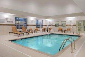 una piscina en una habitación de hotel con sillas y mesas en Courtyard by Marriott Columbus New Albany, en New Albany