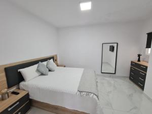 een witte slaapkamer met een groot bed en een spiegel bij ENZO SUITE in Las Palmas de Gran Canaria