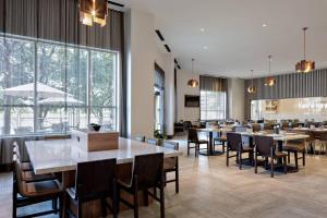 a restaurant with tables and chairs and large windows at Marriott Dallas Las Colinas in Irving