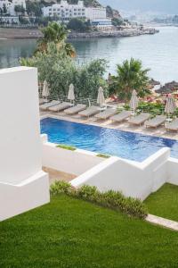 a pool with chairs and umbrellas next to the water at Prive Hotel Bodrum - Adult Only in Bodrum City
