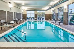 a swimming pool with chairs and tables in a building at Courtyard by Marriott Albany Airport in Albany