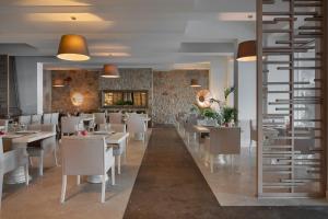 a restaurant with white tables and chairs and a wall at Prive Hotel Bodrum - Adult Only in Bodrum City